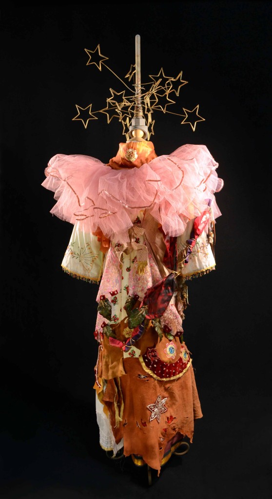 Shamnaic Vestments For A Female Initiate With Spirit Dolls Assemblage by Leslie Ann McQuaide; Assemblage consisting of antique baptismal gown, leather, Middle Eastern embroidery, kiln temperature probe, dressmaker's mannikin, Rosemary Takeda's childhood tutu, hand-embroidered tea towels, willow branch, porcupine quills, religious scapular, metal photo display, porcelain dolls, hand-made lace, handkerchiefs, paper jewelry, metal stand; 65 x 36 x 24 inches 2016